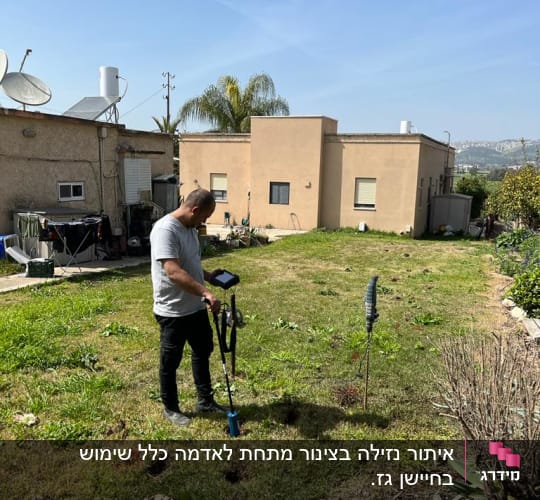 אדם משתמש בגלאי דליפות על דשא בחצר